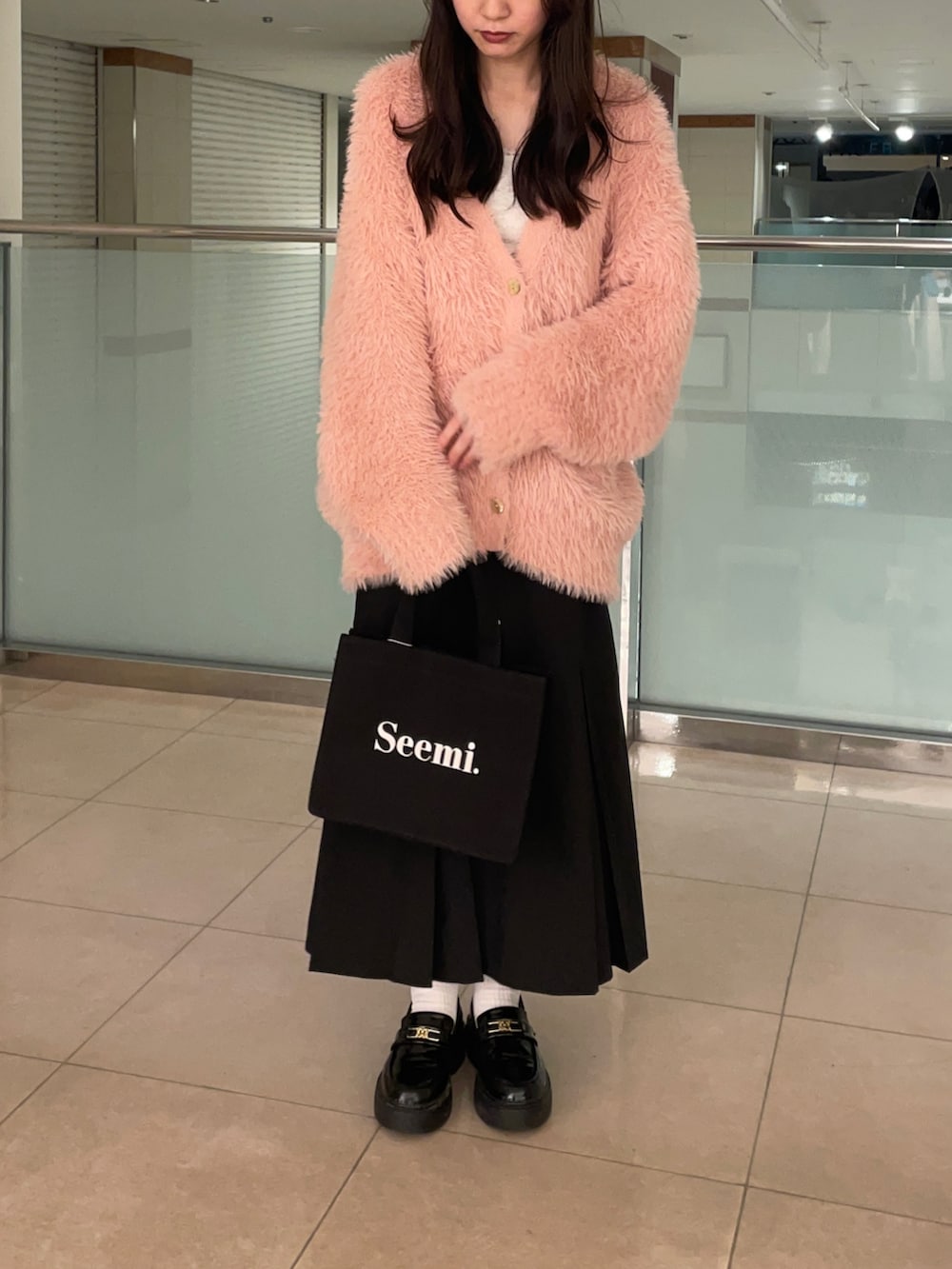 ピンク系のカーディガン/ボレロ、ブラック系のスカート、ブラック系のトートバッグを着用したレディースの秋コーディネートの2枚目の写真