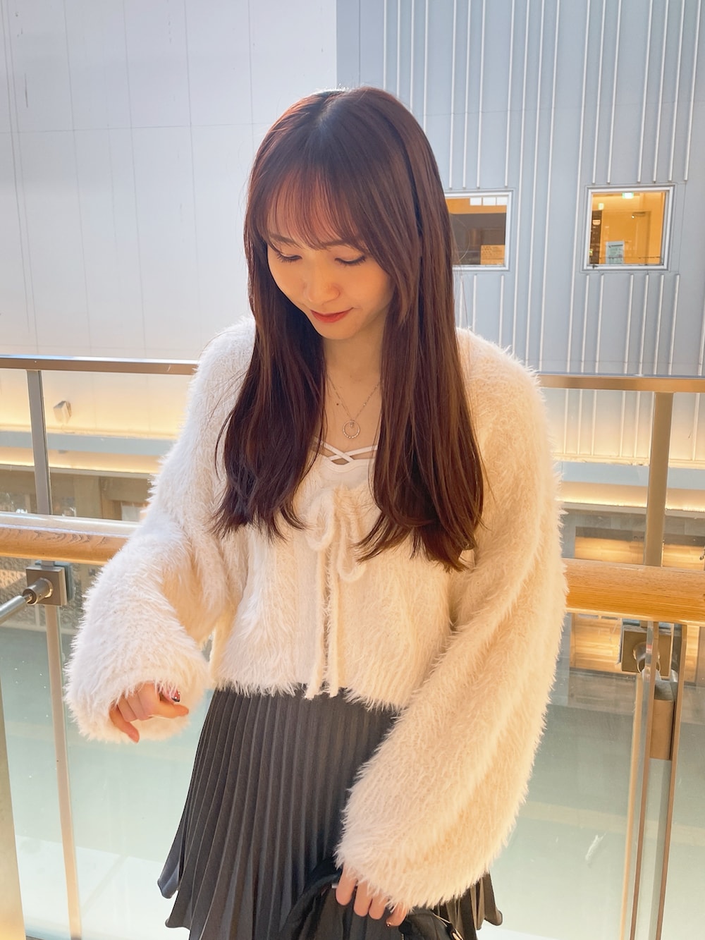 ホワイト系のカーディガン/ボレロ、グレー系のスカート、ブラック系のショルダーバッグを着用したレディースの冬コーディネートの2枚目の写真