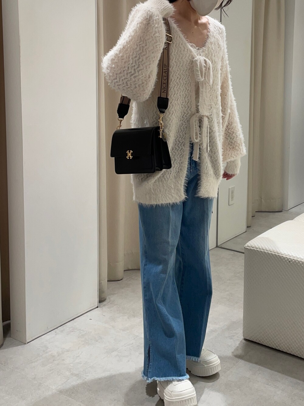 ホワイト系のカーディガン/ボレロ、ブルー系のデニムパンツ、ブラック系のショルダーバッグを着用したレディースの秋コーディネートの3枚目の写真