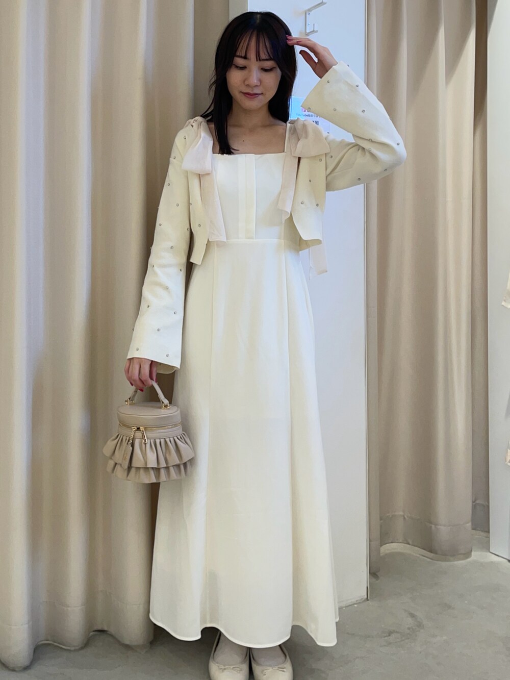 ホワイト系のカーディガン/ボレロ、ホワイト系のワンピース、ベージュ系のショルダーバッグを着用したレディースの秋コーディネートの2枚目の写真