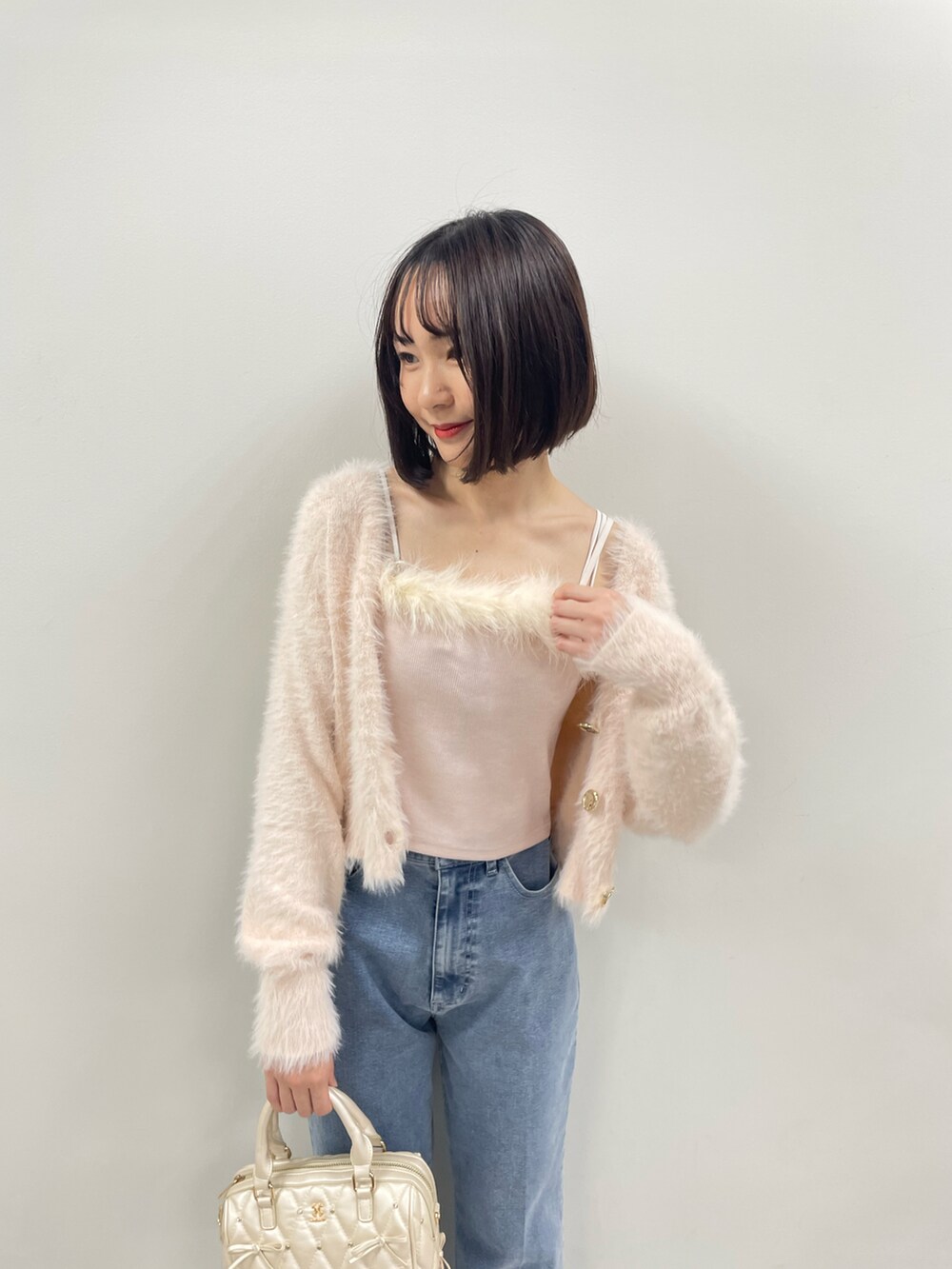 ピンク系のカーディガン/ボレロ、ホワイト系のボストンバッグ、ブルー系のデニムパンツを着用したレディースの秋コーディネートの4枚目の写真