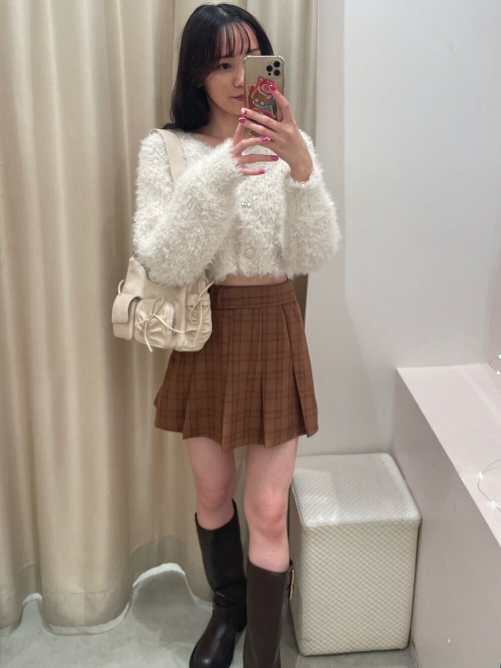 ホワイト系のカーディガン/ボレロ、ベージュ系のスカート、ブラウン系のブーツを着用したレディースの秋コーディネートの3枚目の写真