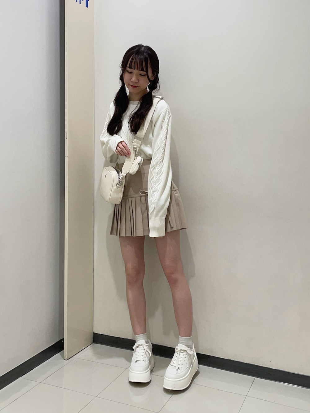ホワイト系のニット/セーター、ベージュ系のスカート、ホワイト系のボディバッグ/ウエストポーチを着用したレディースの春コーディネートの3枚目の写真