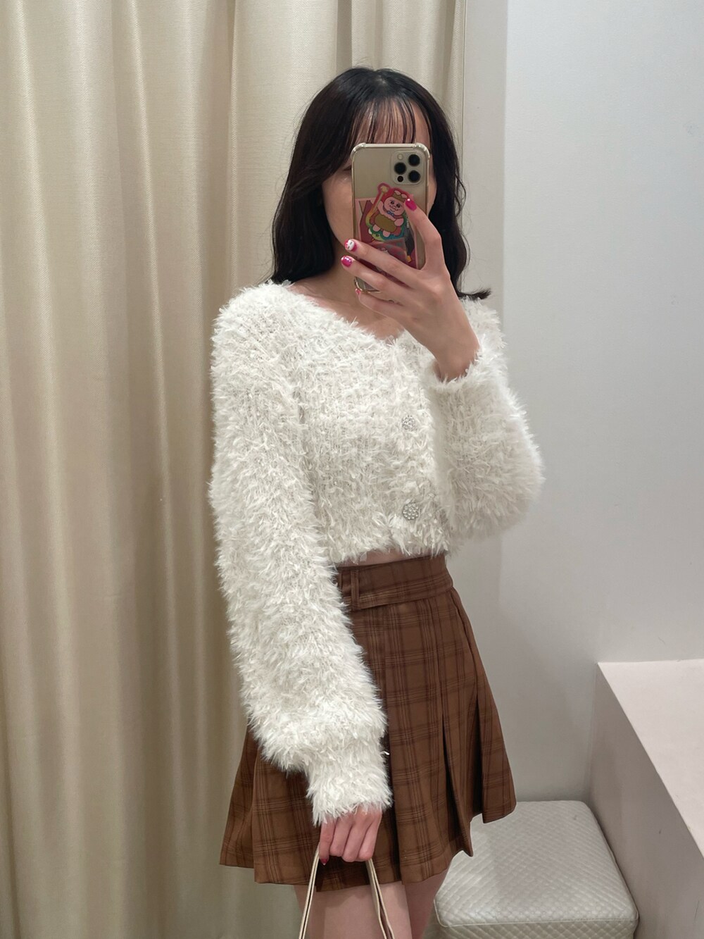 ホワイト系のカーディガン/ボレロ、ベージュ系のスカート、ブラウン系のブーツを着用したレディースの秋コーディネートの4枚目の写真