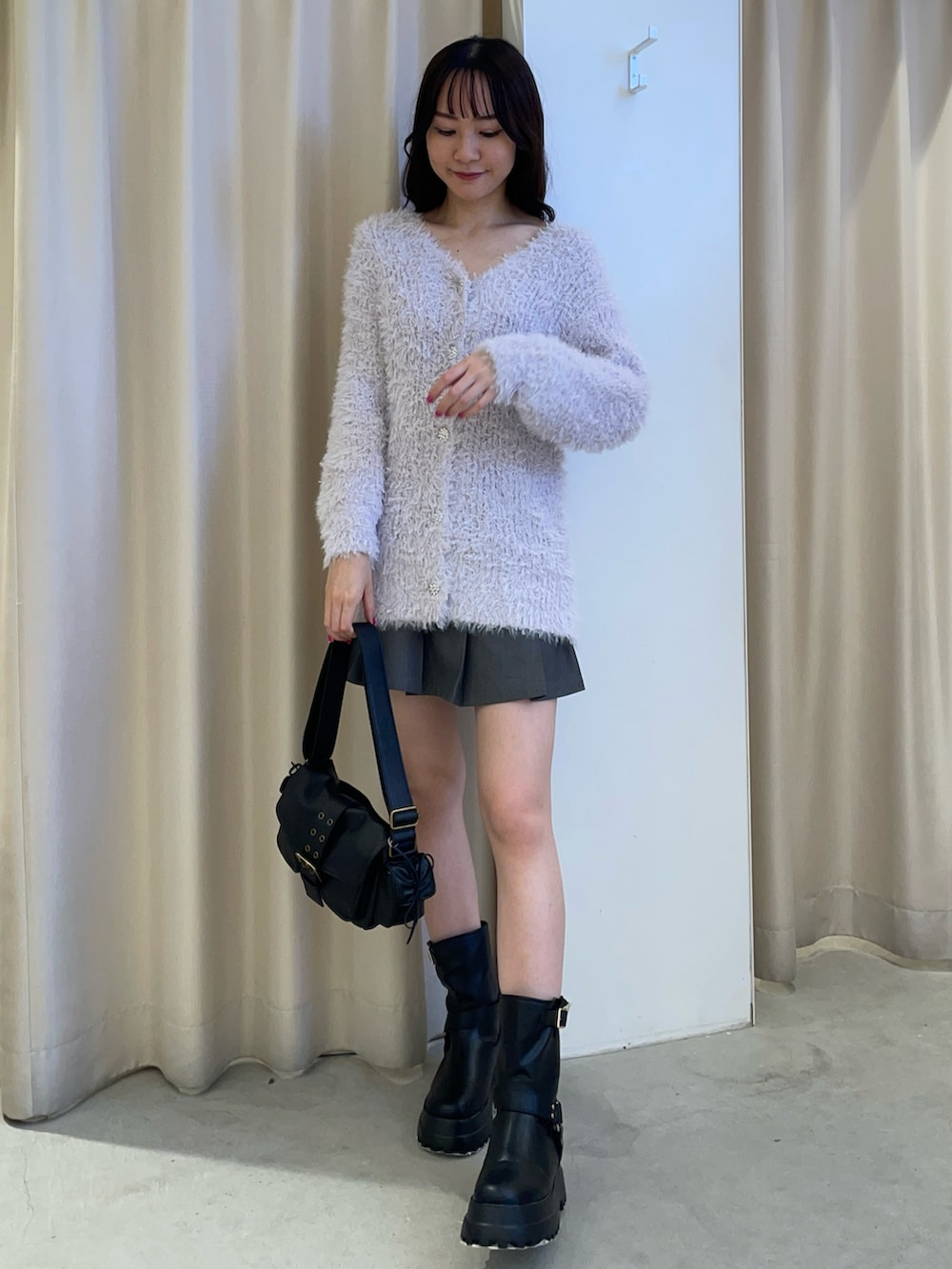 パープル系のカーディガン/ボレロ、ブラック系のショルダーバッグ、ブラック系のブーツを着用したレディースの秋コーディネートの2枚目の写真