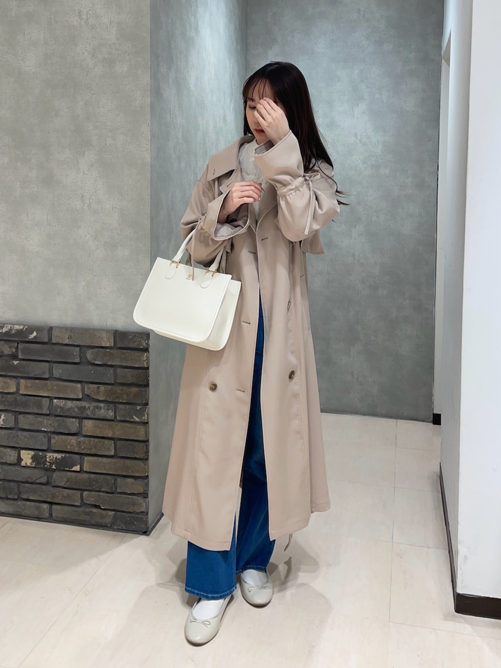 ホワイト系のTシャツ/カットソー、ブルー系のデニムパンツ、ベージュ系のトレンチコートを着用したレディースの春コーディネートの3枚目の写真
