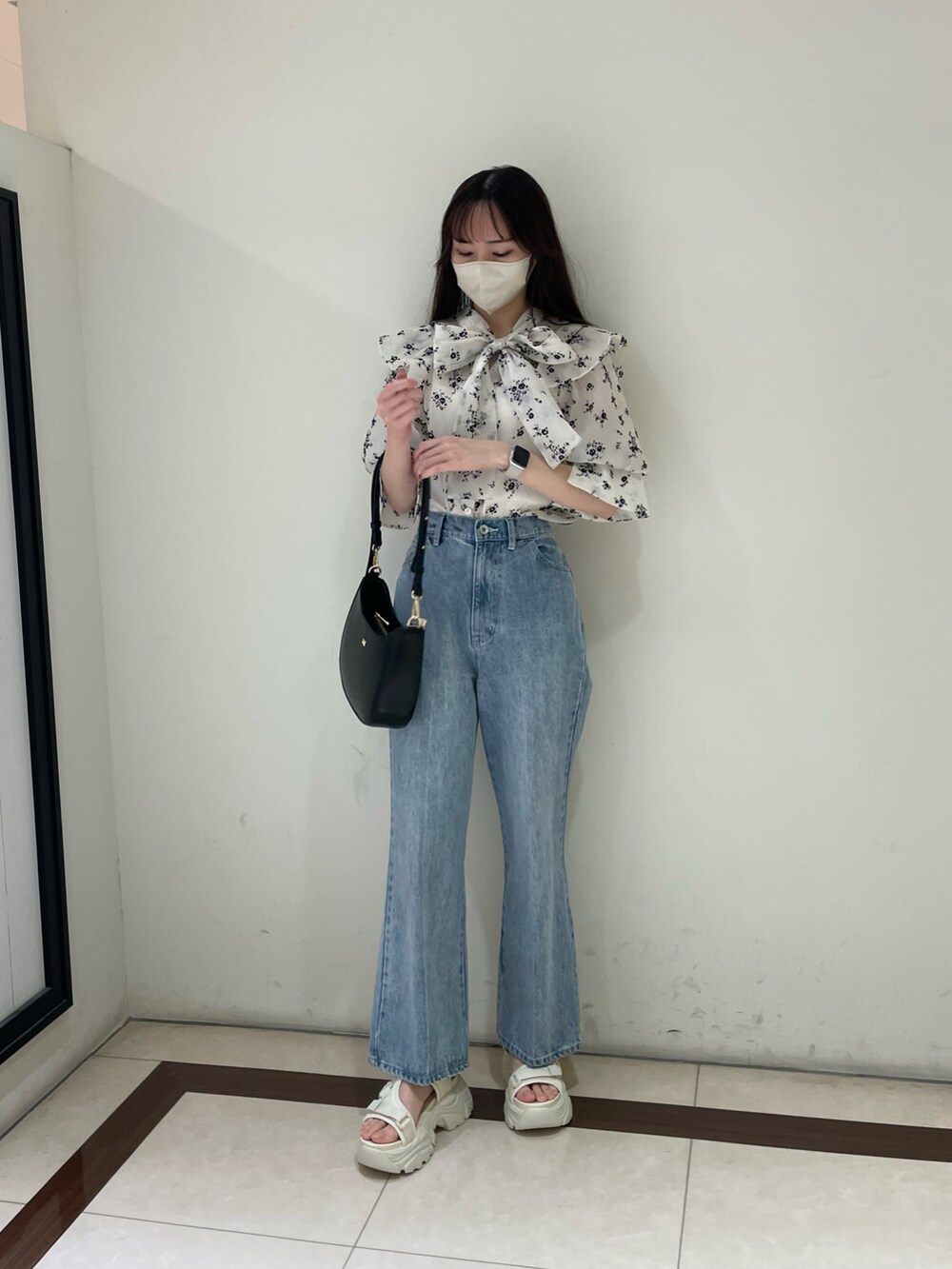 ホワイト系のワンピース、ブルー系のデニムパンツ、ブラック系のショルダーバッグを着用したレディースの春コーディネートの2枚目の写真