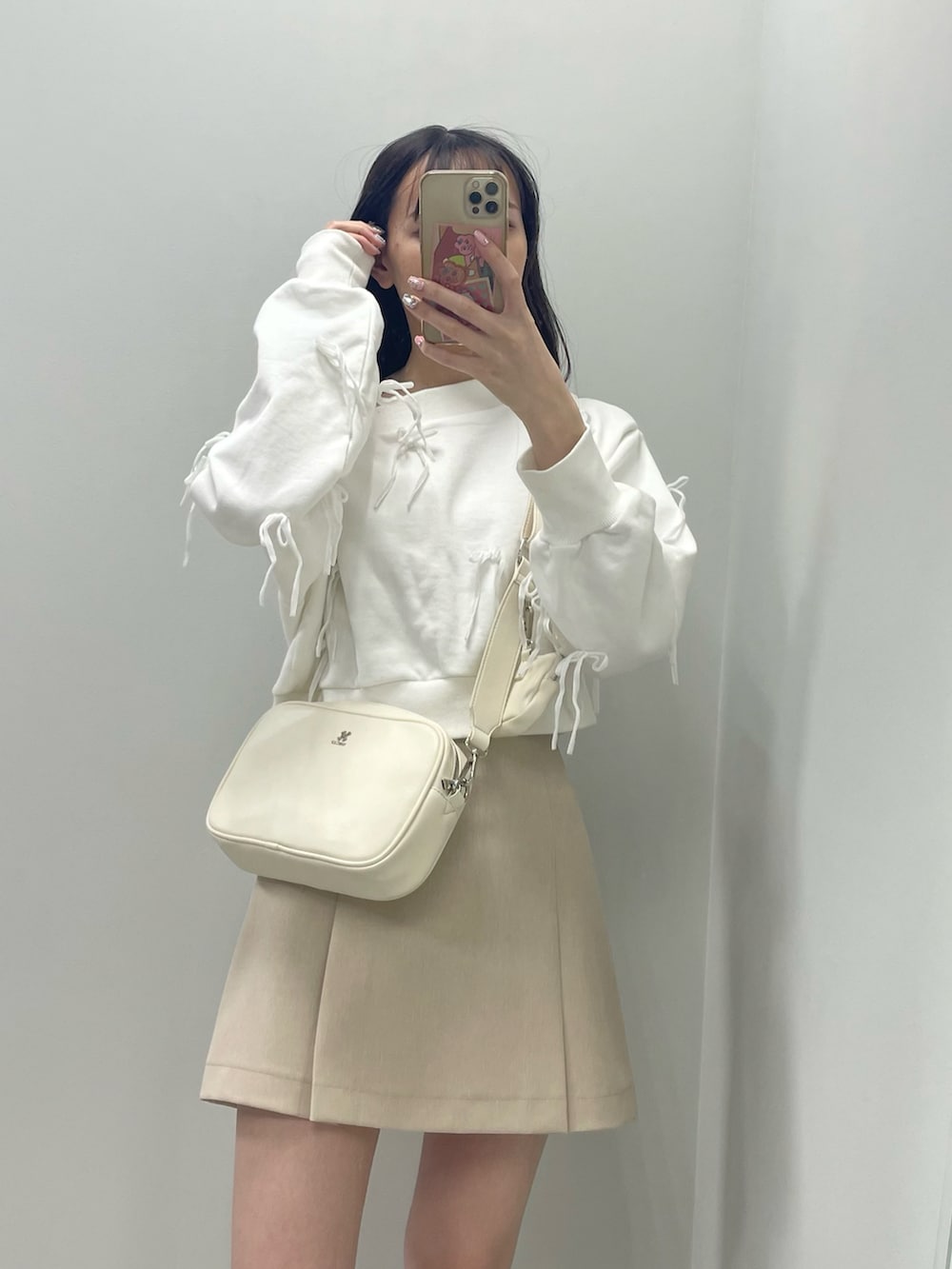ホワイト系のスウェット、ベージュ系のスカート、ホワイト系のボディバッグ/ウエストポーチを着用したレディースの春コーディネートの3枚目の写真