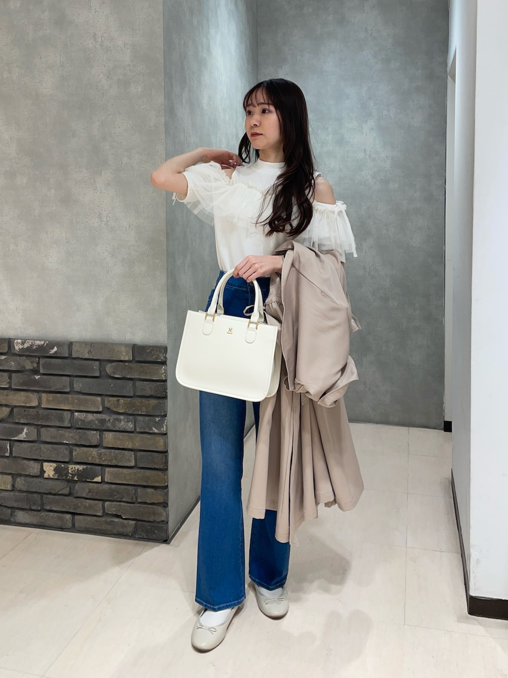 ホワイト系のTシャツ/カットソー、ブルー系のデニムパンツ、ベージュ系のトレンチコートを着用したレディースの春コーディネートの2枚目の写真