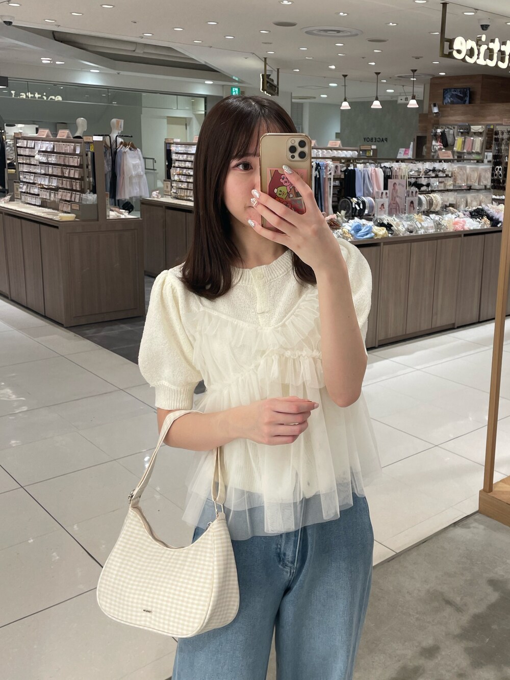 ホワイト系のアンサンブル、ブルー系のデニムパンツ、ベージュ系のショルダーバッグを着用したレディースの春コーディネートの2枚目の写真