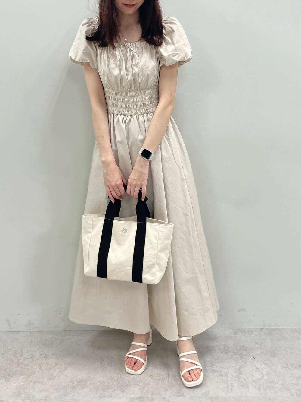 ベージュ系のワンピース、ホワイト系のサンダルを着用したレディースの春コーディネートの2枚目の写真