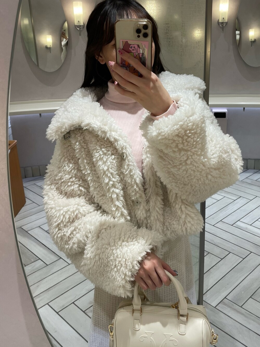 ホワイト系のブルゾン、ホワイト系のスカート、ホワイト系のハンドバッグを着用したレディースの秋コーディネートの2枚目の写真