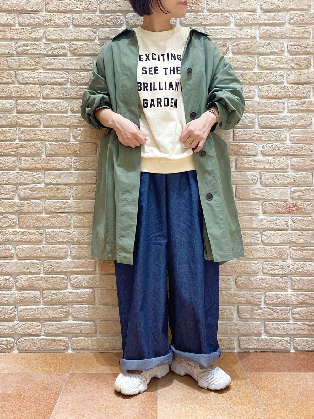 ホワイト系のTシャツ/カットソー、グリーン系のステンカラーコート、ブルー系のデニムパンツを着用したレディースの春コーディネートの4枚目の写真