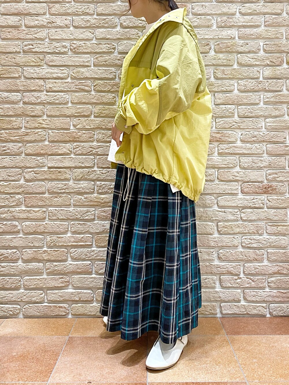 イエロー系のブルゾン、ホワイト系のTシャツ/カットソー、ブルー系のスカートを着用したレディースの春コーディネートの3枚目の写真