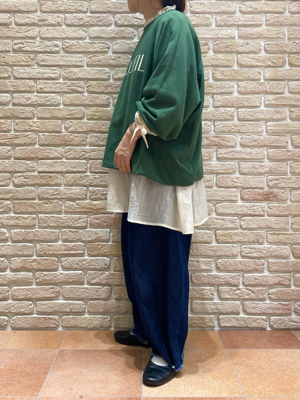 グリーン系のTシャツ/カットソー、ホワイト系のシャツ/ブラウス、ブルー系のデニムパンツを着用したレディースの秋コーディネートの3枚目の写真