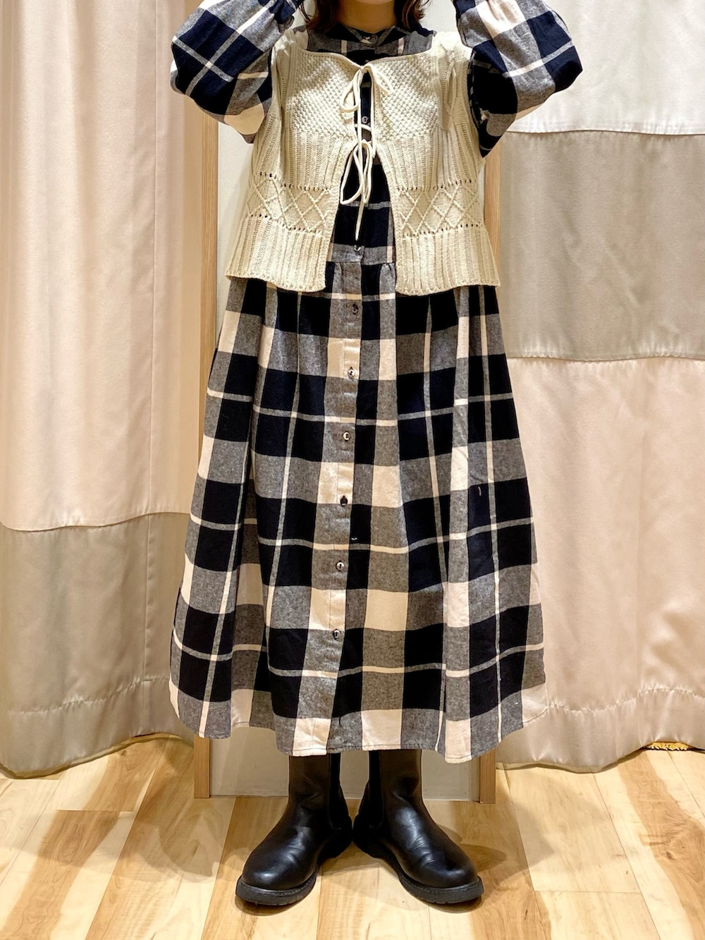 ブラック系のワンピース、ホワイト系のベスト、ブラック系のブーツを着用したレディースの冬コーディネートの4枚目の写真