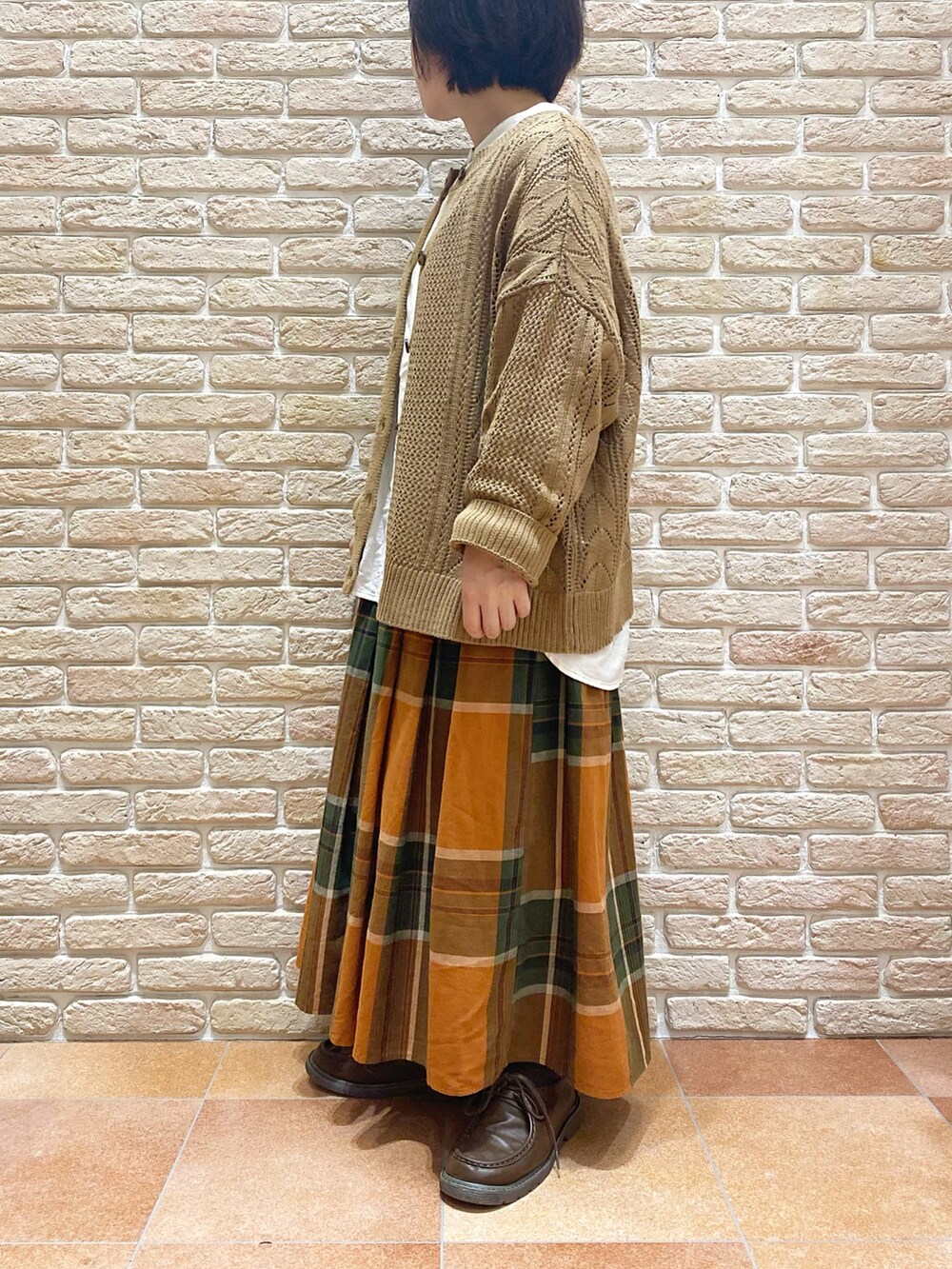 オレンジ系のスカート、ホワイト系のシャツ/ブラウス、ベージュ系のニット/セーターを着用したレディースの秋コーディネートの4枚目の写真
