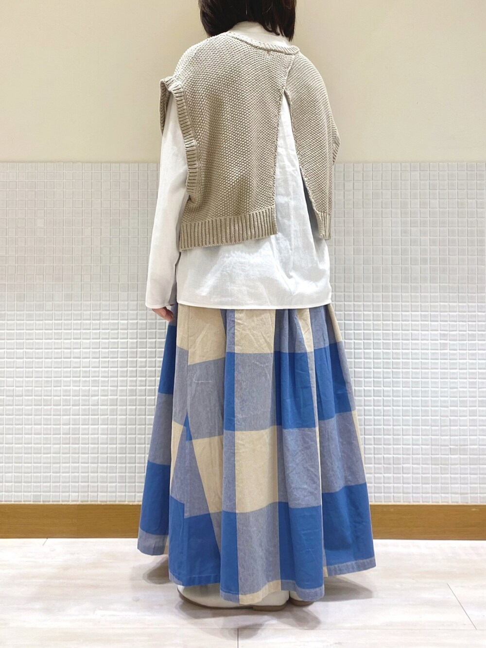 ベージュ系のベスト、ホワイト系のシャツ/ブラウス、ブルー系のスカートを着用したレディースの冬コーディネートの3枚目の写真