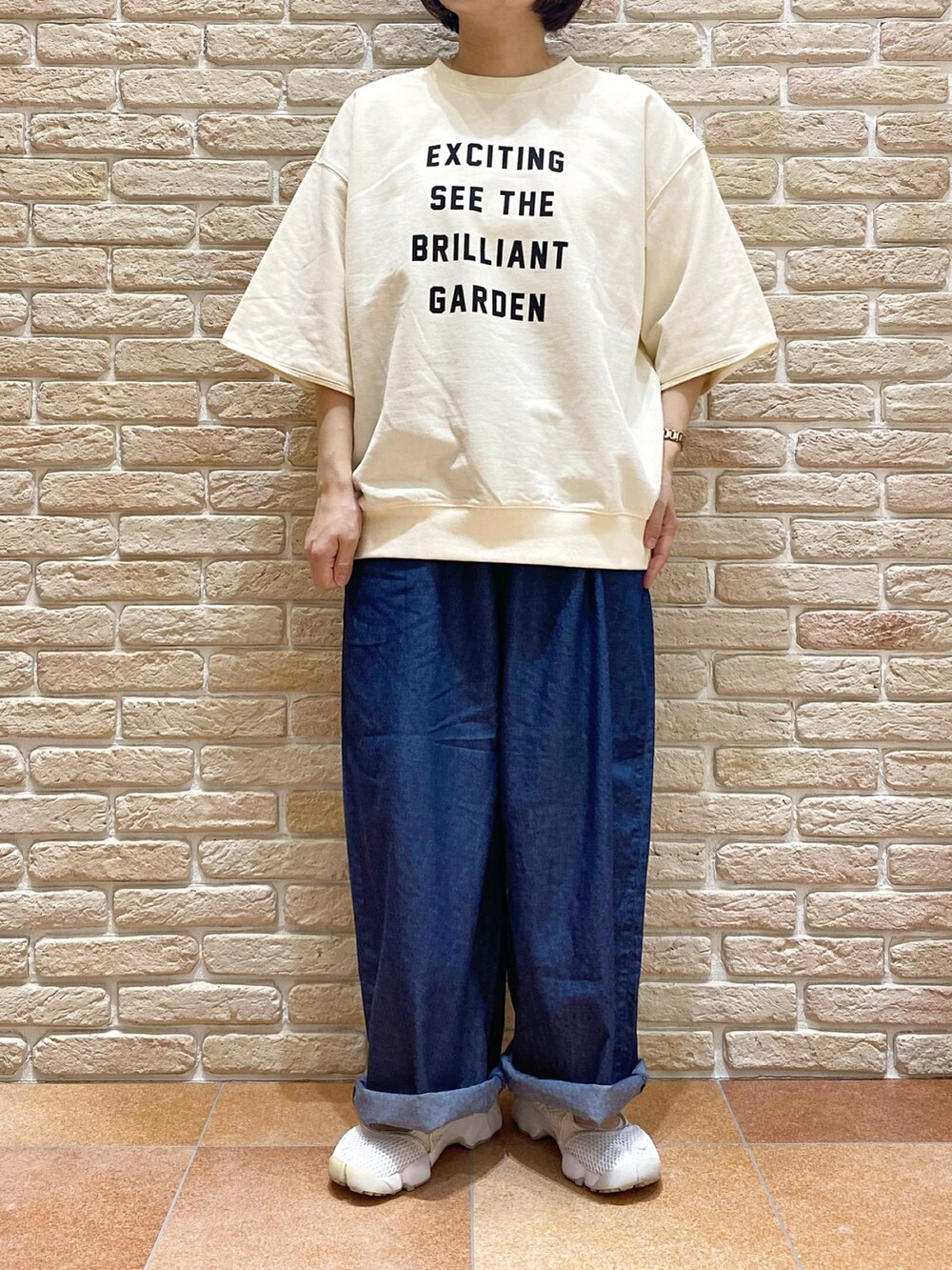 ホワイト系のTシャツ/カットソー、グリーン系のステンカラーコート、ブルー系のデニムパンツを着用したレディースの春コーディネートの5枚目の写真