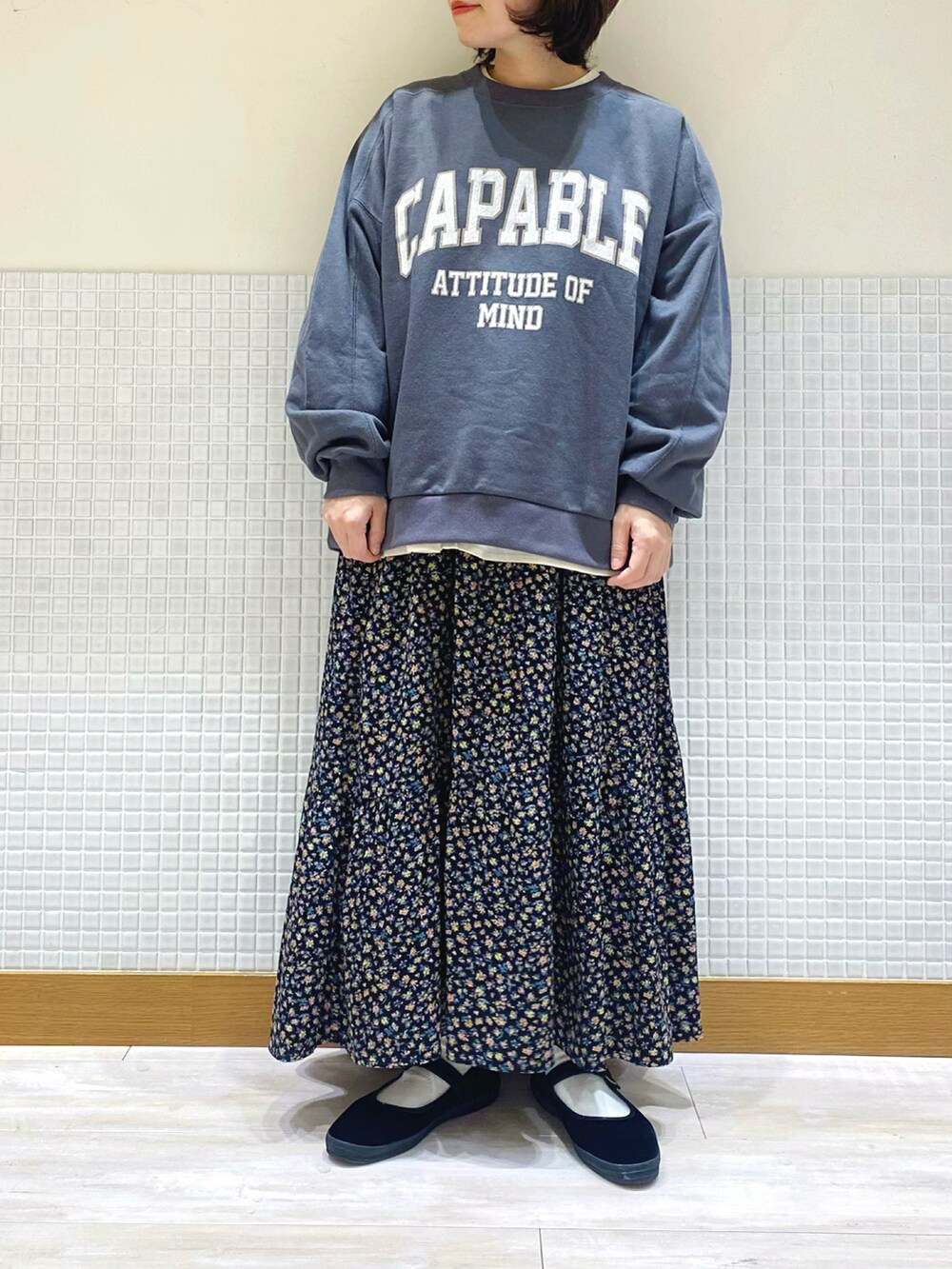 グレー系のスウェット、ホワイト系のシャツ/ブラウス、ブラック系のスカートを着用したレディースの冬コーディネートの2枚目の写真