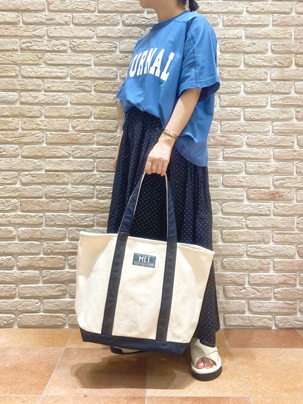 ブルー系のTシャツ/カットソー、ブラック系のスカート、ホワイト系のサンダルを着用したレディースの春コーディネートの2枚目の写真