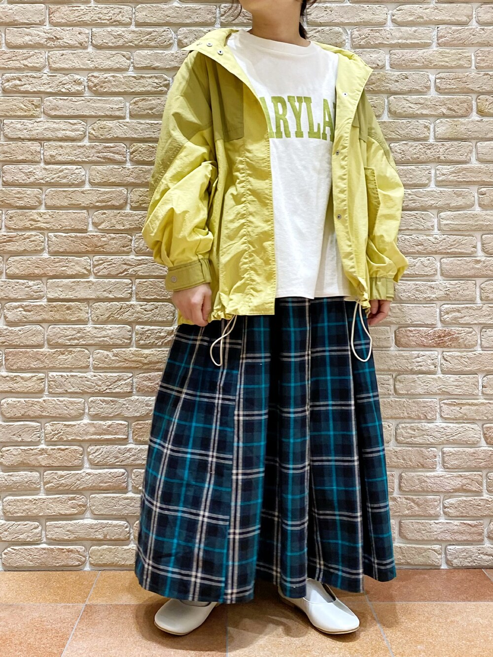 イエロー系のブルゾン、ホワイト系のTシャツ/カットソー、ブルー系のスカートを着用したレディースの春コーディネートの2枚目の写真