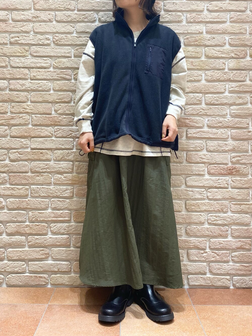 グレー系のTシャツ/カットソー、ブルー系のベスト、グリーン系のスカートを着用したレディースの秋コーディネートの4枚目の写真
