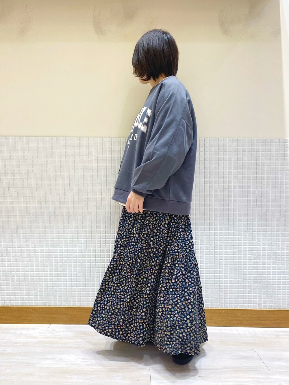 グレー系のスウェット、ホワイト系のシャツ/ブラウス、ブラック系のスカートを着用したレディースの冬コーディネートの3枚目の写真