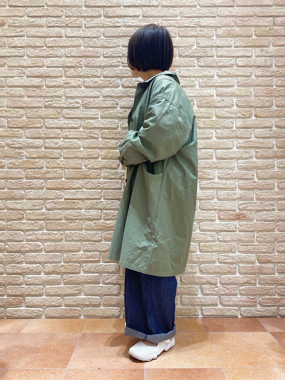 ホワイト系のTシャツ/カットソー、グリーン系のステンカラーコート、ブルー系のデニムパンツを着用したレディースの春コーディネートの3枚目の写真