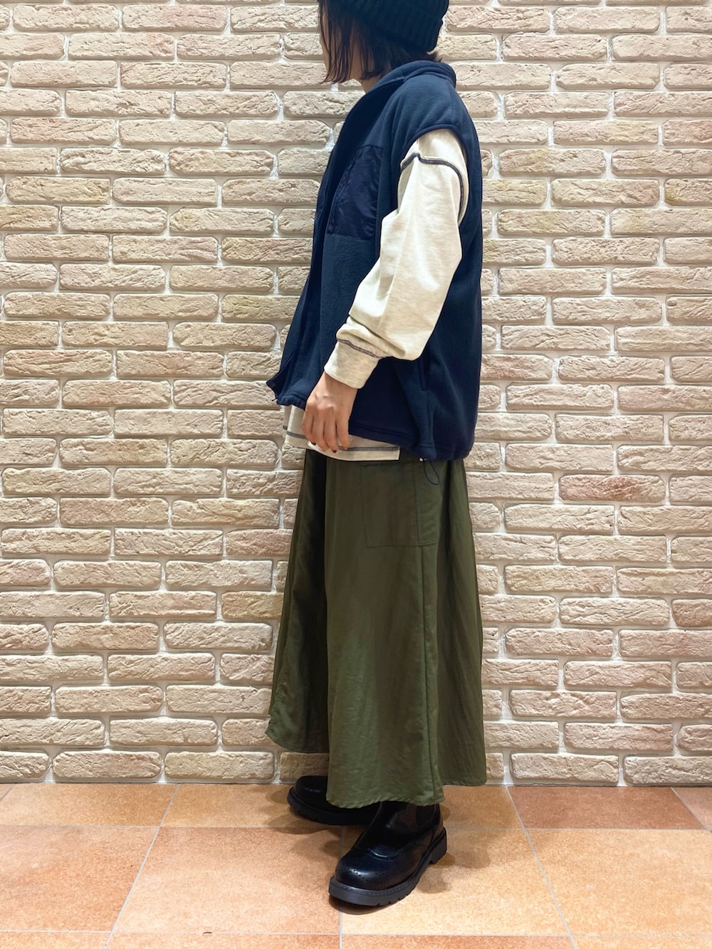 グレー系のTシャツ/カットソー、ブルー系のベスト、グリーン系のスカートを着用したレディースの秋コーディネートの3枚目の写真