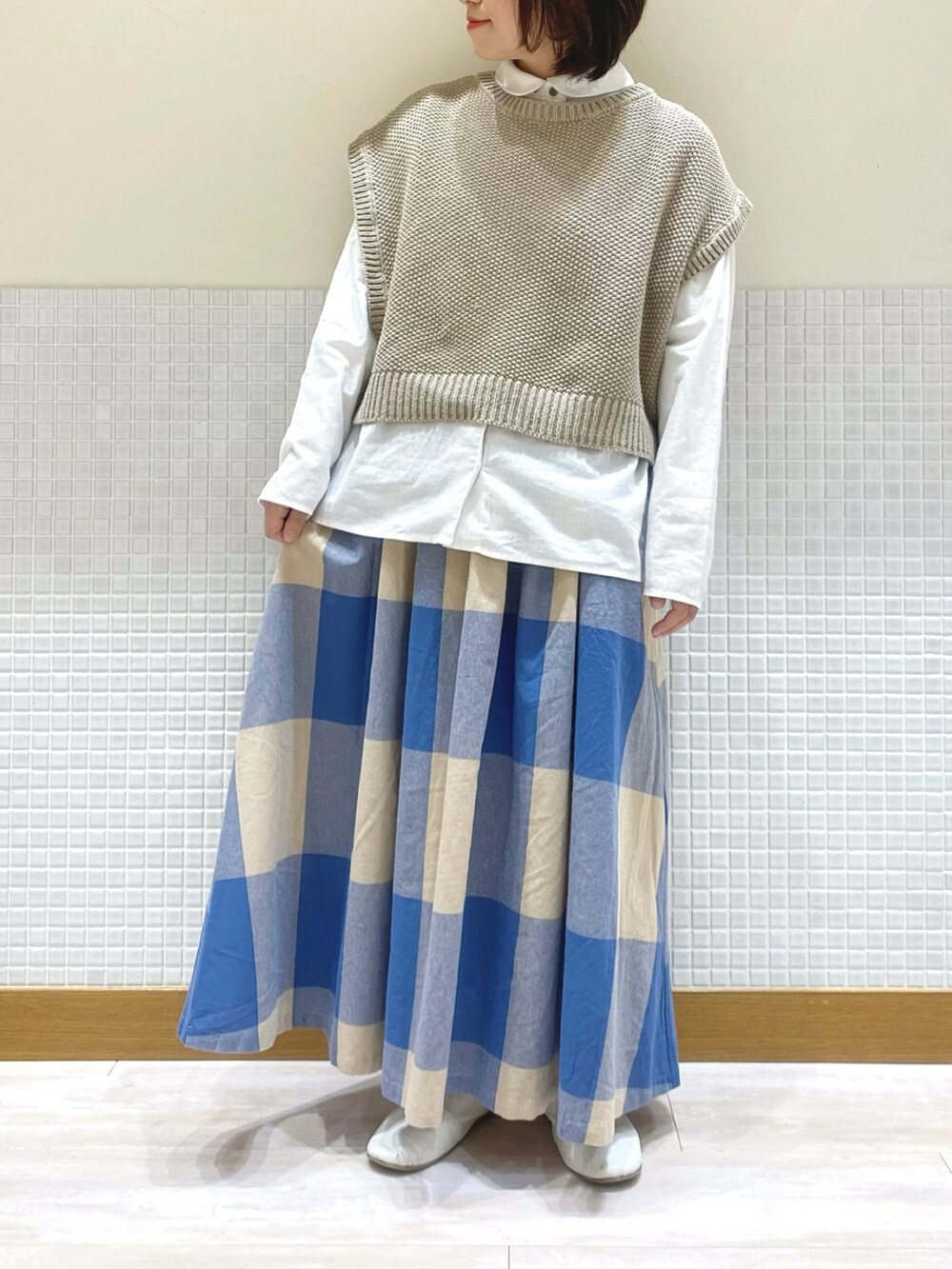 ベージュ系のベスト、ホワイト系のシャツ/ブラウス、ブルー系のスカートを着用したレディースの冬コーディネートの2枚目の写真