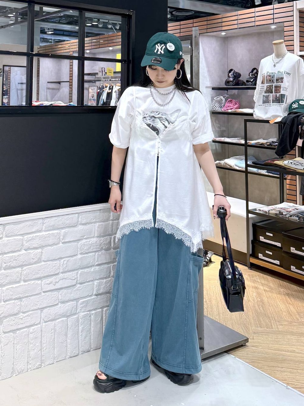 ブラック系のショルダーバッグ、ブラック系のサンダル、ホワイト系のTシャツ/カットソーを着用したレディースの春コーディネートの3枚目の写真