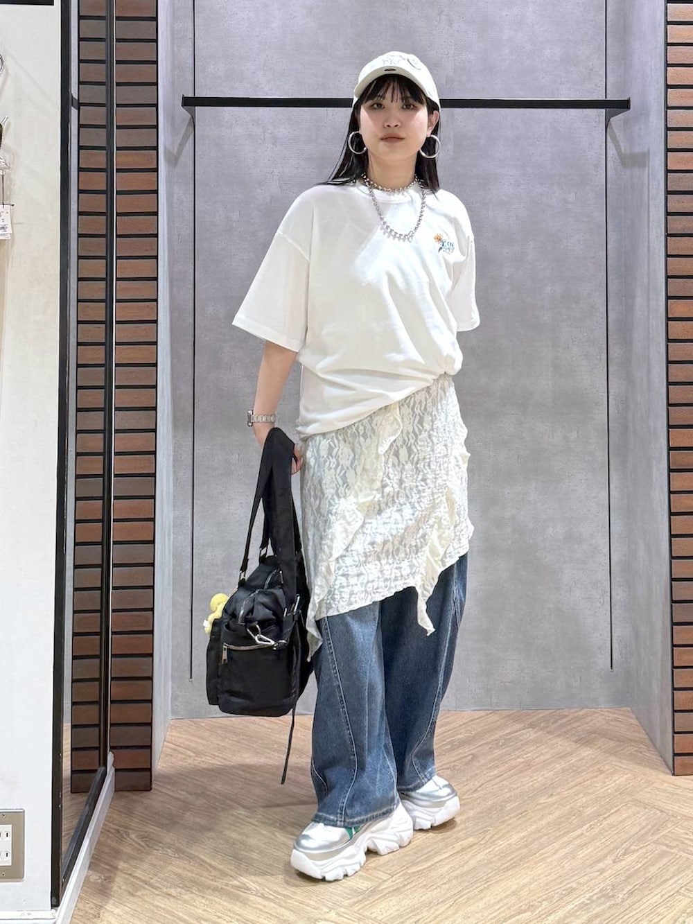 ホワイト系のスニーカー、ブラック系のボストンバッグ、ブルー系のデニムパンツを着用したレディースの春コーディネートの7枚目の写真