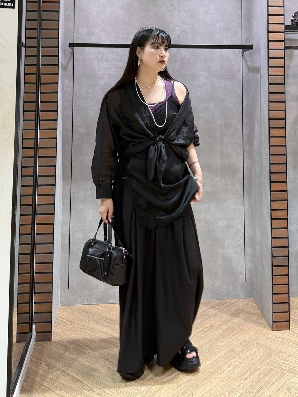 ブラック系のショルダーバッグ、ブラック系のチュニック、ブラック系のスラックスを着用したレディースの夏コーディネートの2枚目の写真
