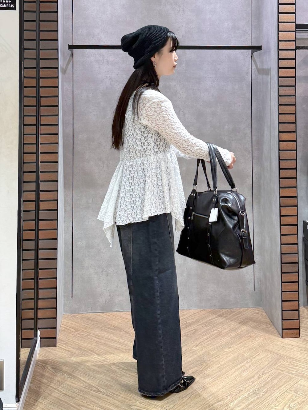 ブラック系のサンダル、ブラック系のボストンバッグ、ブルー系のデニムパンツを着用したレディースの夏コーディネートの2枚目の写真