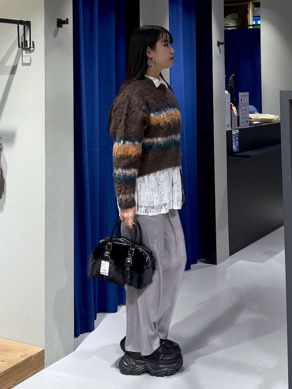 ブラック系のブーツ、ブラウン系のボストンバッグ、ホワイト系のシャツ/ブラウスを着用したレディースの冬コーディネートの2枚目の写真