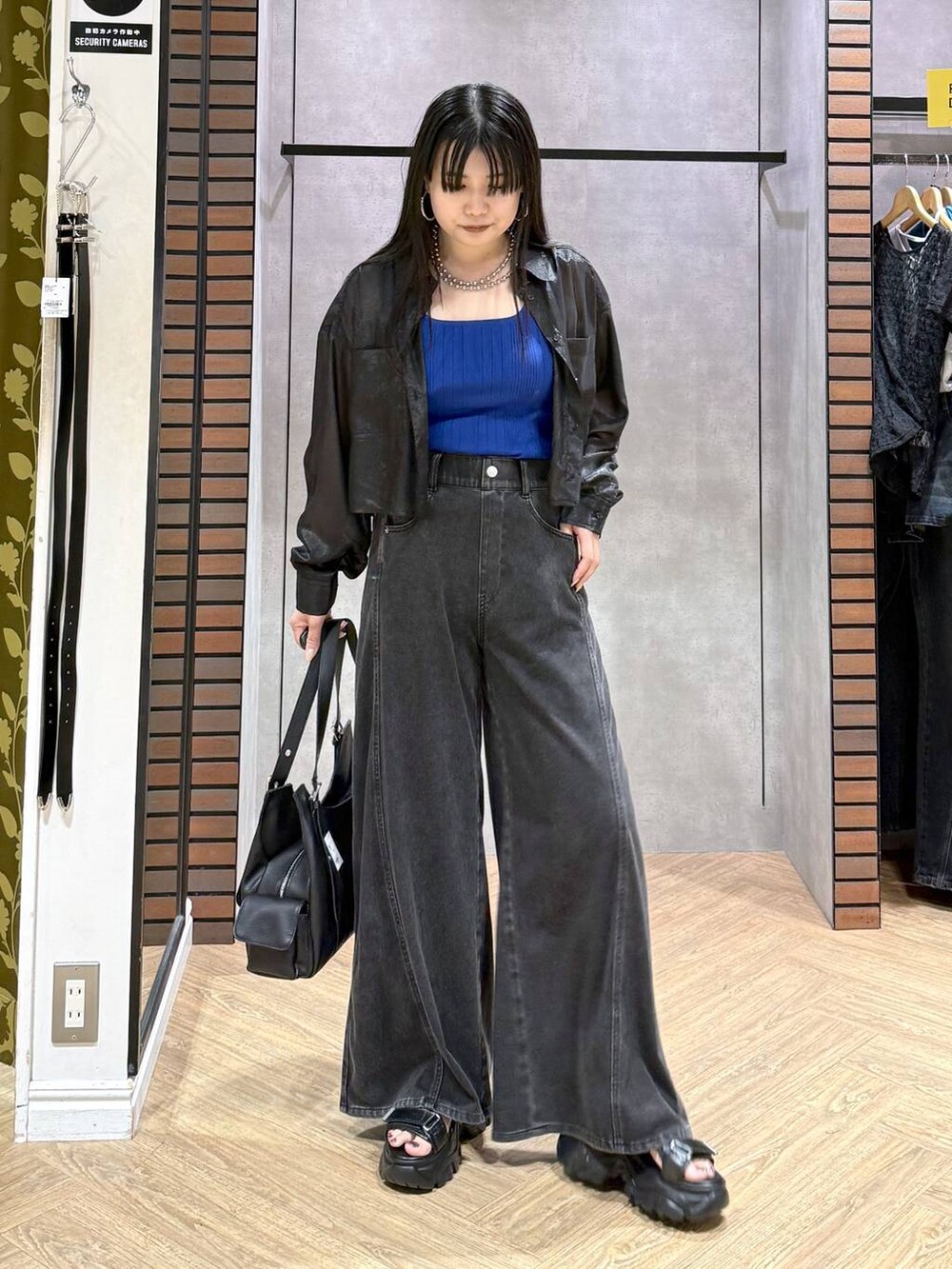 ブラック系のデニムパンツ、ブルー系のタンクトップ、ブラック系のサンダルを着用したレディースの夏コーディネートの5枚目の写真