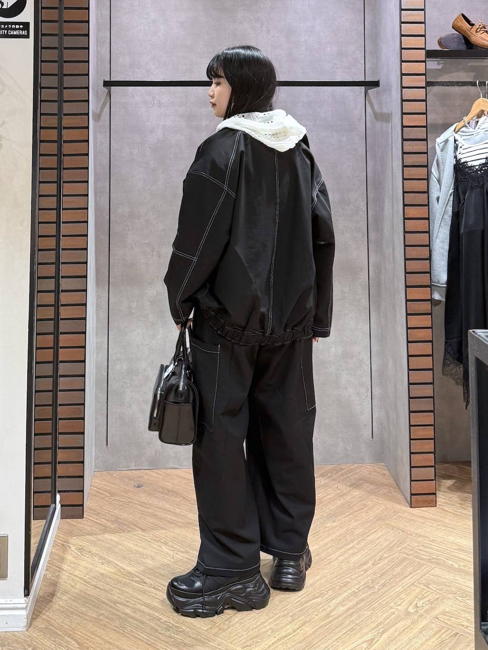 ブラック系のスニーカー、ブラック系のショルダーバッグ、ブルー系のタンクトップを着用したレディースの春コーディネートの3枚目の写真