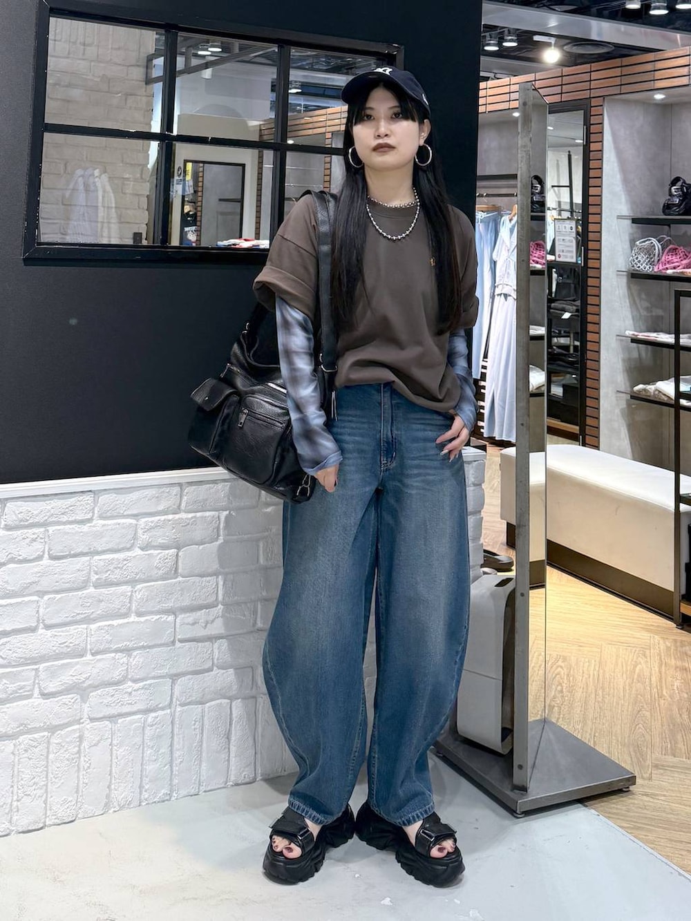 ブラウン系のショルダーバッグ、ブラック系のサンダル、ブラウン系のTシャツ/カットソーを着用したレディースの夏コーディネートの2枚目の写真