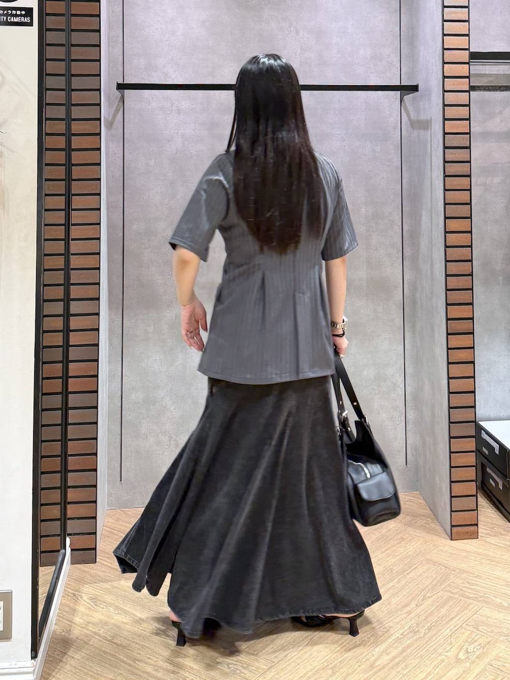 ブラック系のデニムスカート、ブラック系のサンダル、ブラック系のハンドバッグを着用したレディースの夏コーディネートの3枚目の写真