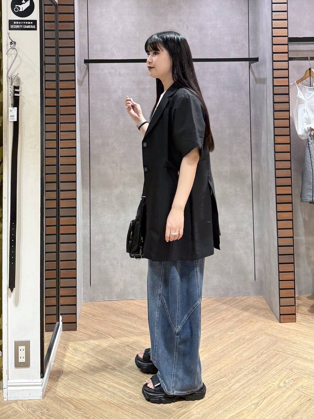 ブラック系のショルダーバッグ、ブルー系のデニムパンツ、ブラック系のサンダルを着用したレディースの春コーディネートの7枚目の写真
