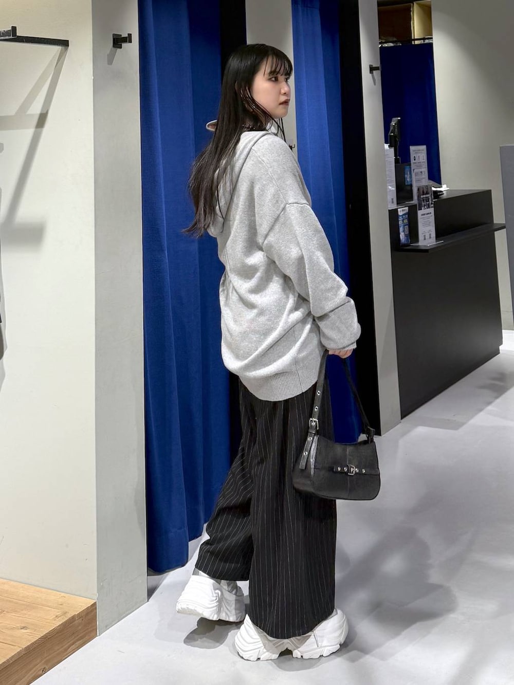 ホワイト系のスニーカー、ブラック系のハンドバッグ、ホワイト系のニット/セーターを着用したレディースの冬コーディネートの7枚目の写真