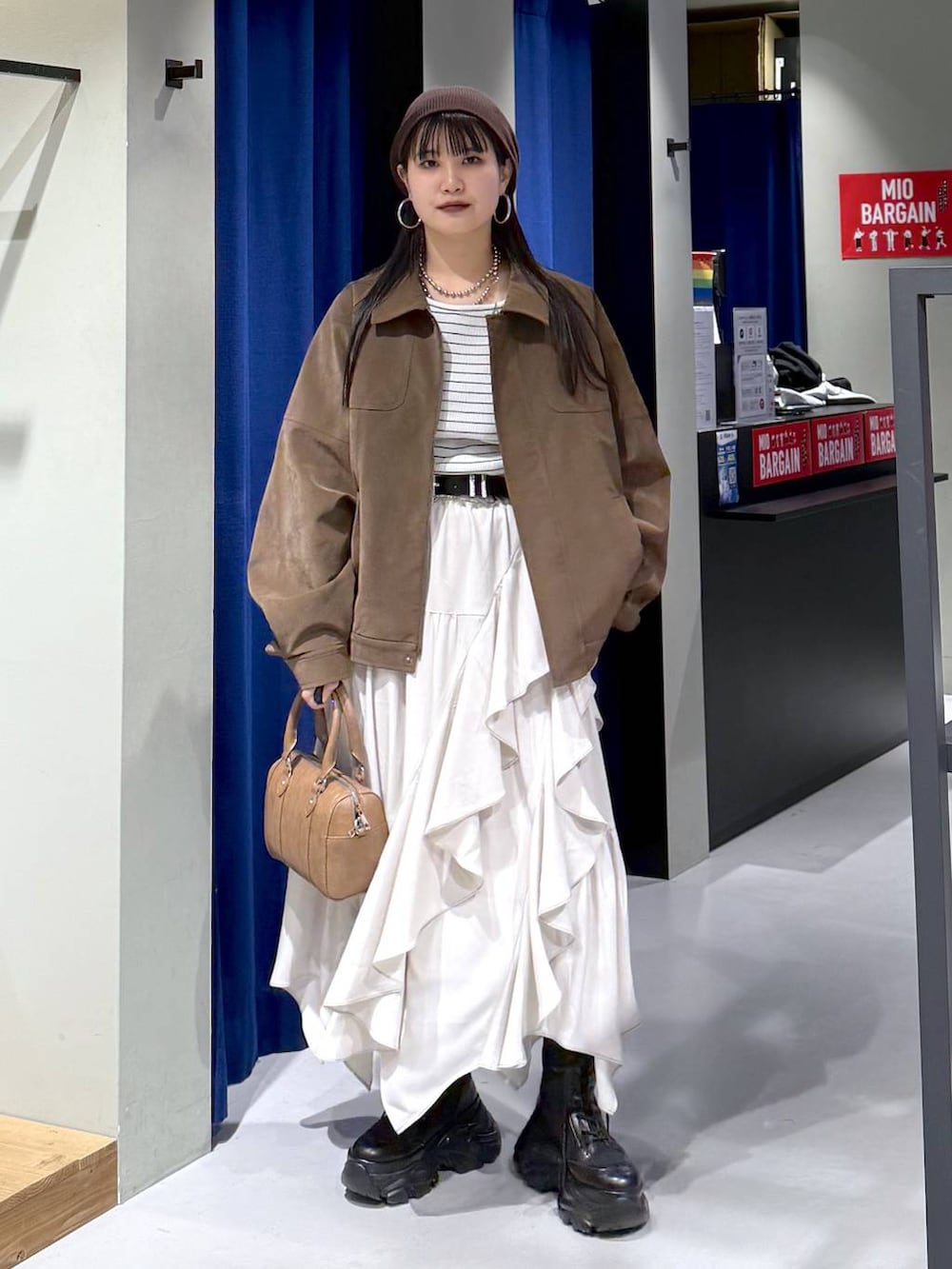 ブラック系のブーツ、ベージュ系のスカート、ブラウン系のボストンバッグを着用したレディースの春コーディネートの8枚目の写真