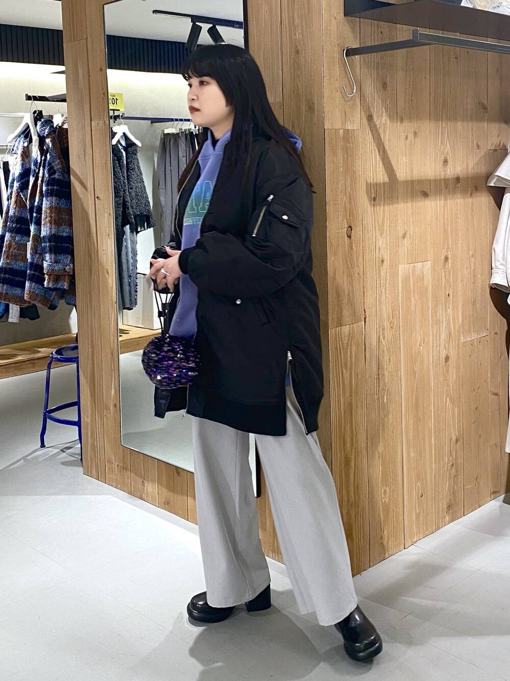 グレー系のスラックス、ブラック系のブーツ、ブラック系のショルダーバッグを着用したレディースの冬コーディネートの3枚目の写真