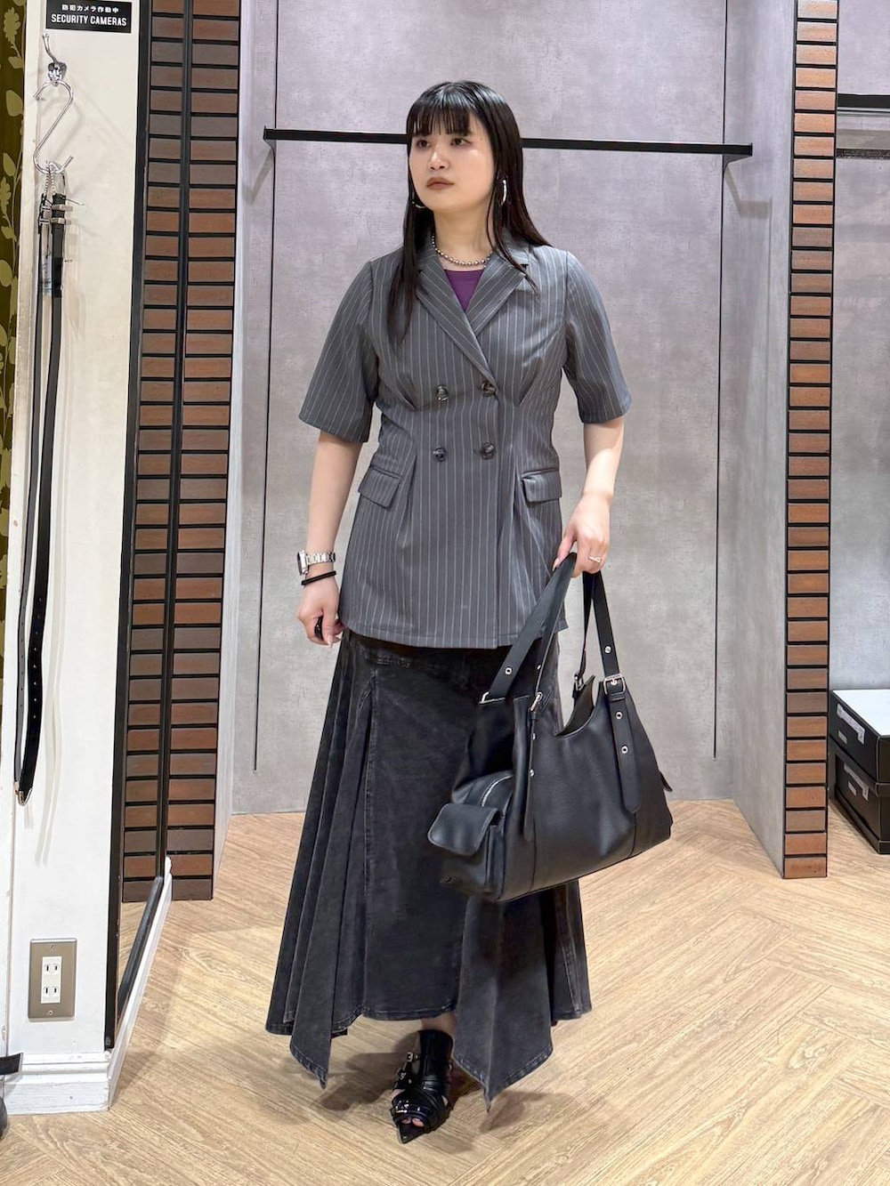 ブラック系のデニムスカート、ブラック系のサンダル、ブラック系のハンドバッグを着用したレディースの夏コーディネートの4枚目の写真