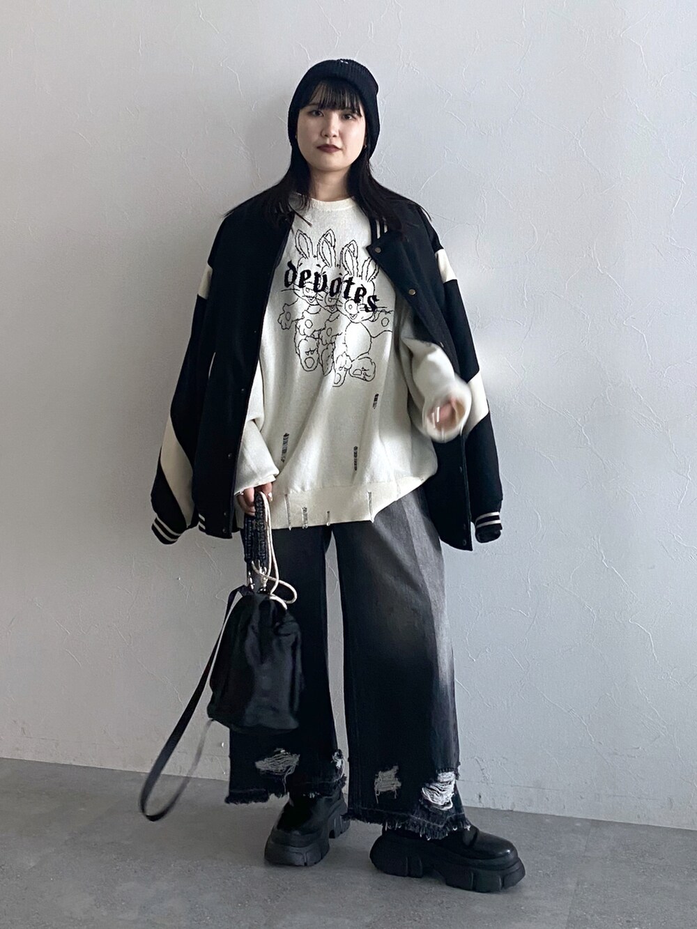 ブラック系のデニムパンツ、ブラック系のスタジャン、ホワイト系のニット/セーターを着用したレディースの秋コーディネートの5枚目の写真