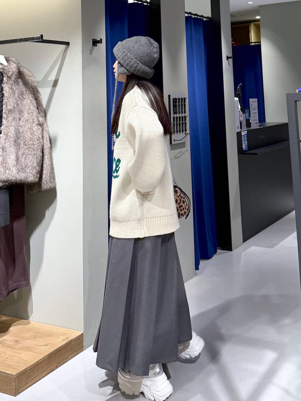 ホワイト系のブーツ、ホワイト系のニット/セーター、グレー系のスカートを着用したレディースの冬コーディネートの6枚目の写真