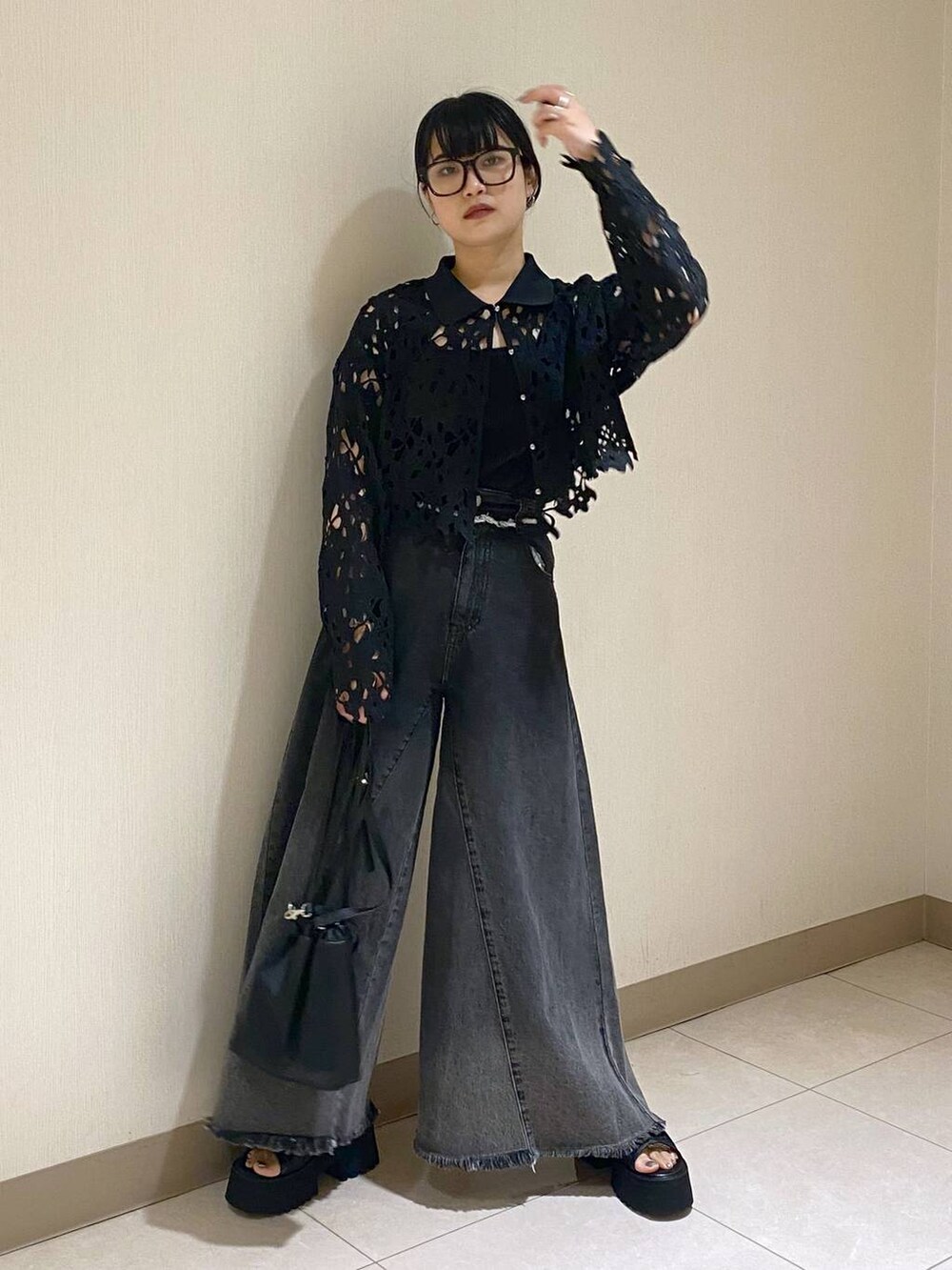 ブラック系のタンクトップ、ブラック系のショルダーバッグ、ブラック系のデニムパンツを着用したレディースの夏コーディネートの3枚目の写真