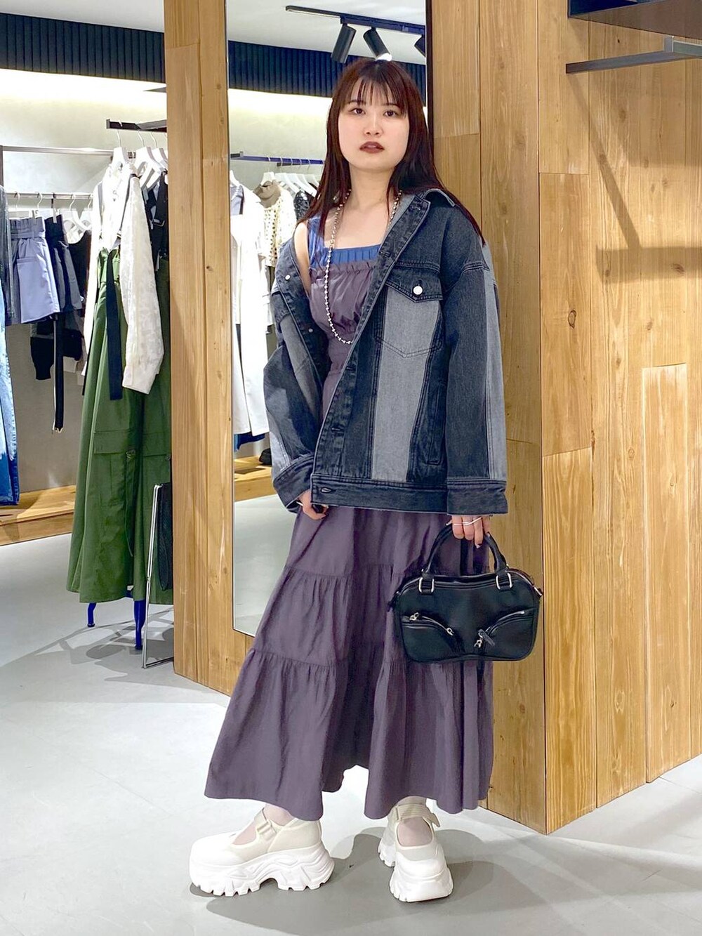 ブルー系のタンクトップ、ブラック系のデニムジャケット、ブラック系のボストンバッグを着用したレディースの春コーディネートの6枚目の写真