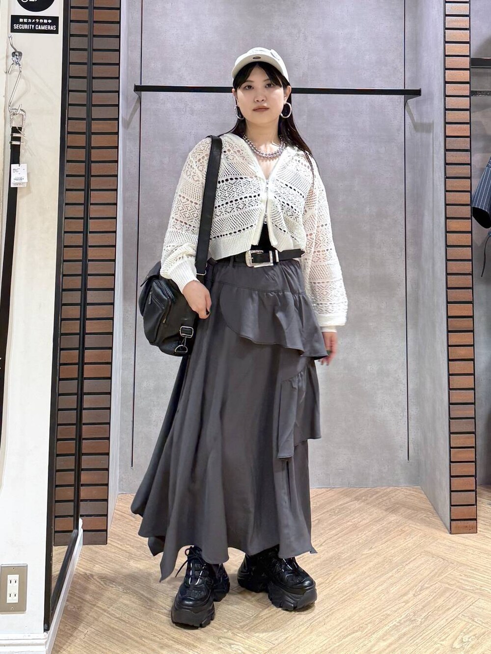 グレー系のスカート、ブラック系のスニーカー、ホワイト系のパーカーを着用したレディースの夏コーディネートの9枚目の写真